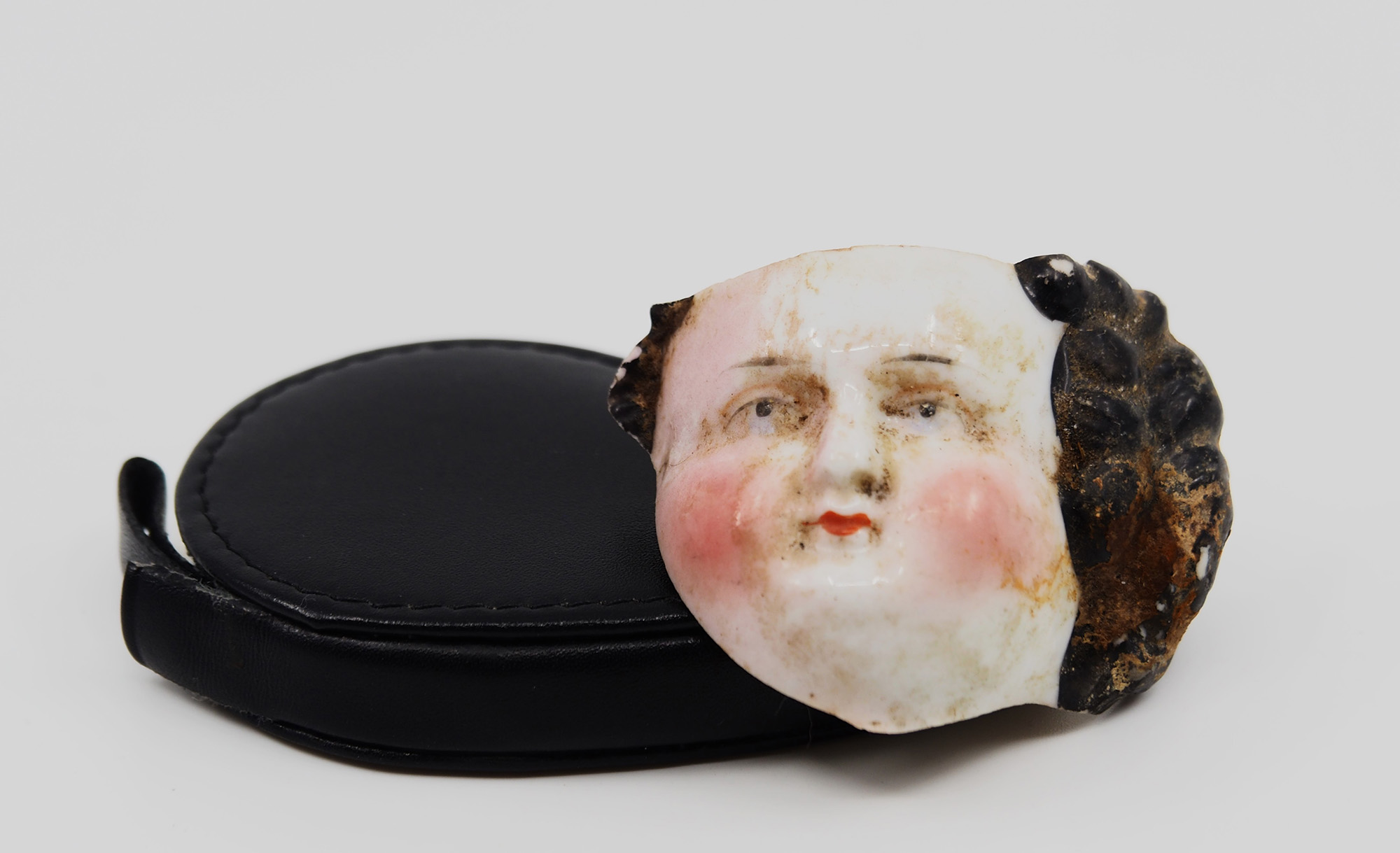 7. Doll head, partial, porcelain, 2 in long, 1.5 in wide (a)